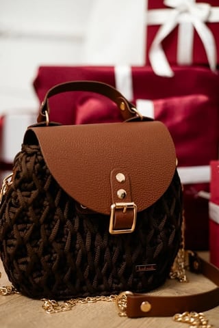 Brown leather backpack with black quilted fabric, gold hardware, and chain strap