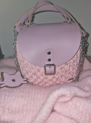 Pink leather shoulder bag with quilted texture, metal chain straps, and buckle closure
