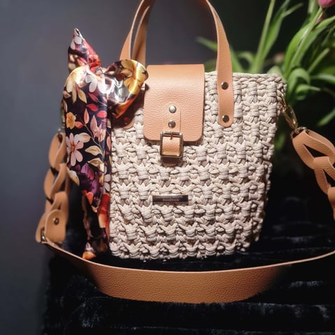 Beige woven tote bag with tan leather handles and floral scarf accent