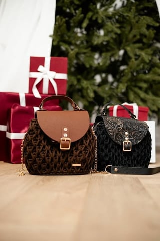 Two fashionable handbags displayed on a wooden surface with holiday gift boxes