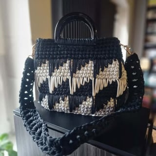 Black and cream woven macramé handbag with fringe detailing and circular black handles