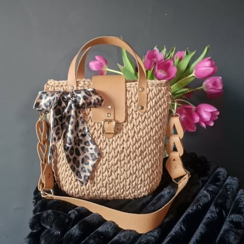 Woven tan handbag with handles, leopard print scarf, and bright pink and green tulips displayed against gray background