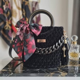 Black quilted handbag with chain detail, colorful silk scarf, and decorative charms