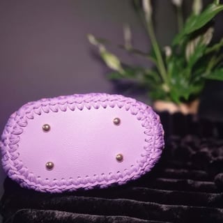 Purple handmade coin purse with decorative stitching and metal studs