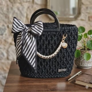Black quilted handbag with black and white striped bow, pearl chain detail