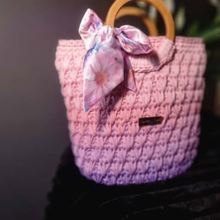 Pink quilted handbag with wooden handles and purple floral scarf bow