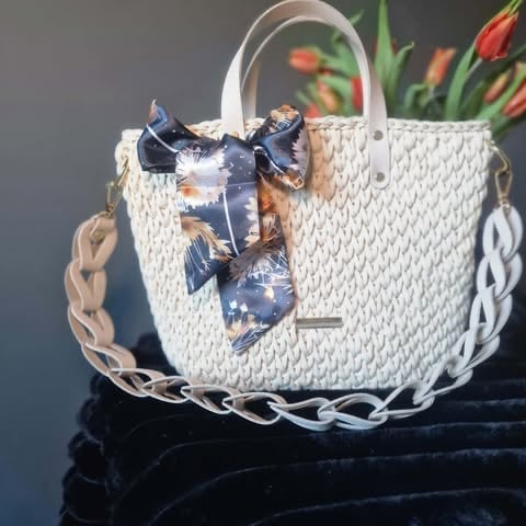 White woven handbag with chain handles, blue floral scarf, and orange tulips in background displayed on velvet surface
