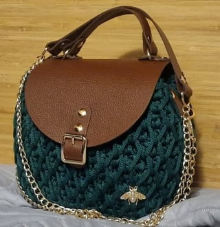 Quilted teal handbag with brown leather flap, gold chain strap, and bee emblem