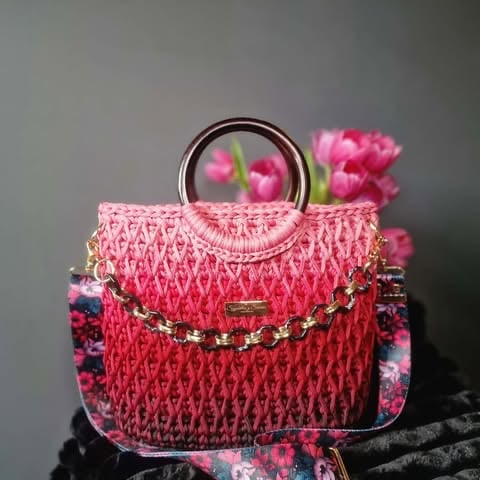 Pink quilted handbag with metallic handles, gold chain strap, and decorative flowers on metal arch handle and sides