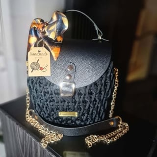Black patterned handbag with gold chain strap, leather top, handmade tag and floral bow